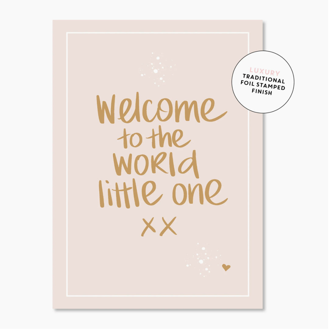 A luxury greeting card with 'Welcome to the world little one' printed in gold foil on a neutral background, with a heart symbol at the bottom right corner.