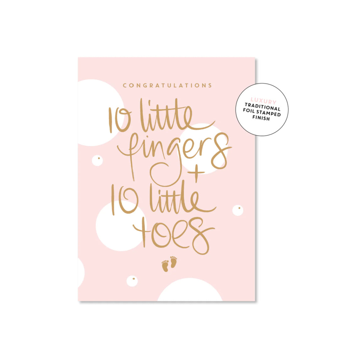 A pink luxury greeting card with gold foil text reading 'CONGRATULATIONS 10 little fingers + 10 little toes' and a small pair of footprints below the text.