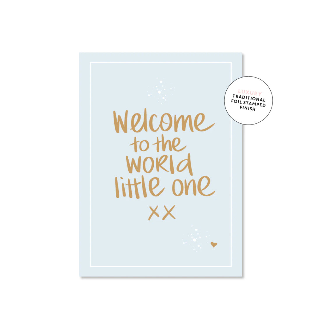 A luxury greeting card with 'Welcome to the world little one' printed in gold foil on a blue background, with a heart symbol at the bottom right corner.