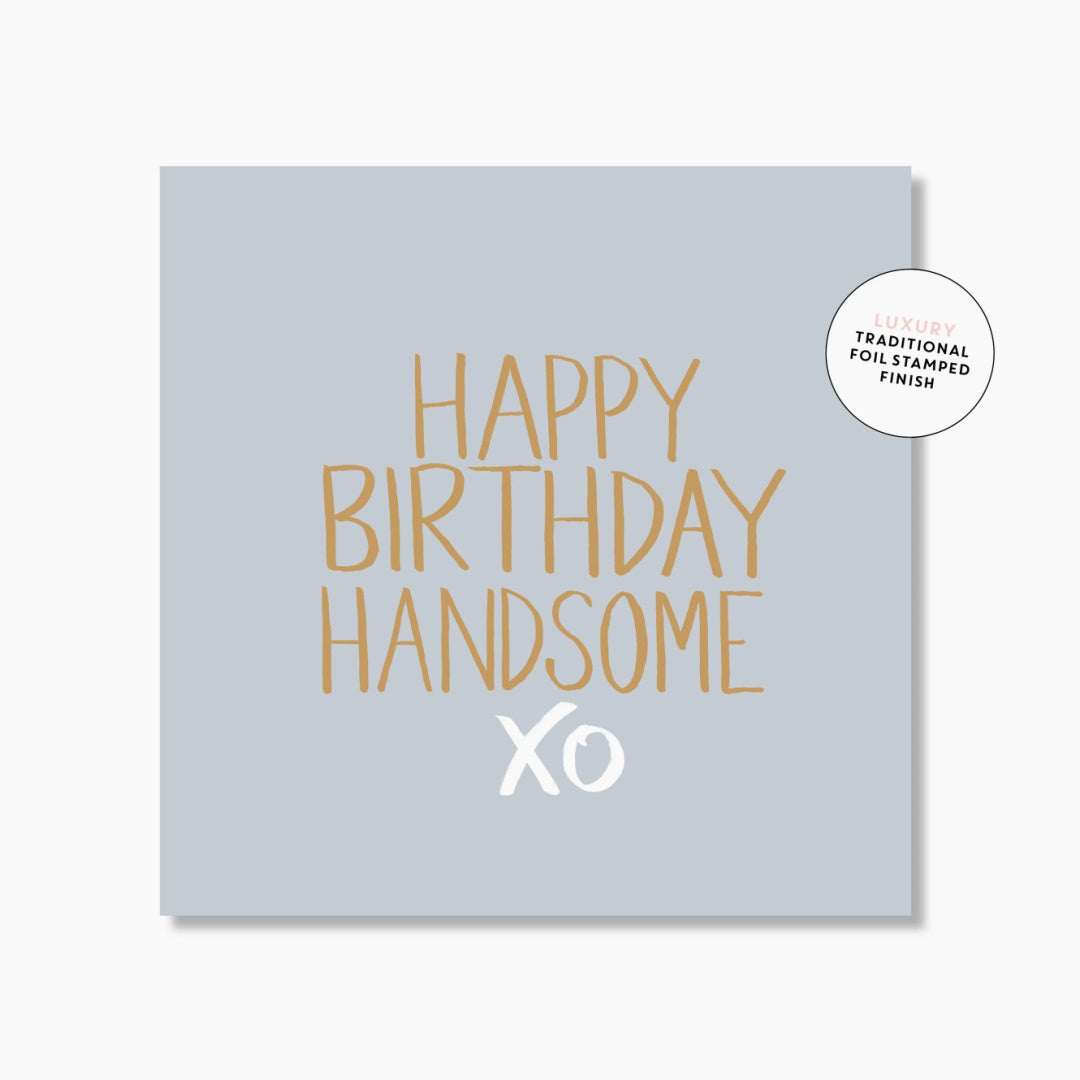 A mini greeting card with &#39;HAPPY BIRTHDAY HANDSOME XO&#39; printed in gold foil on a light blue background. 